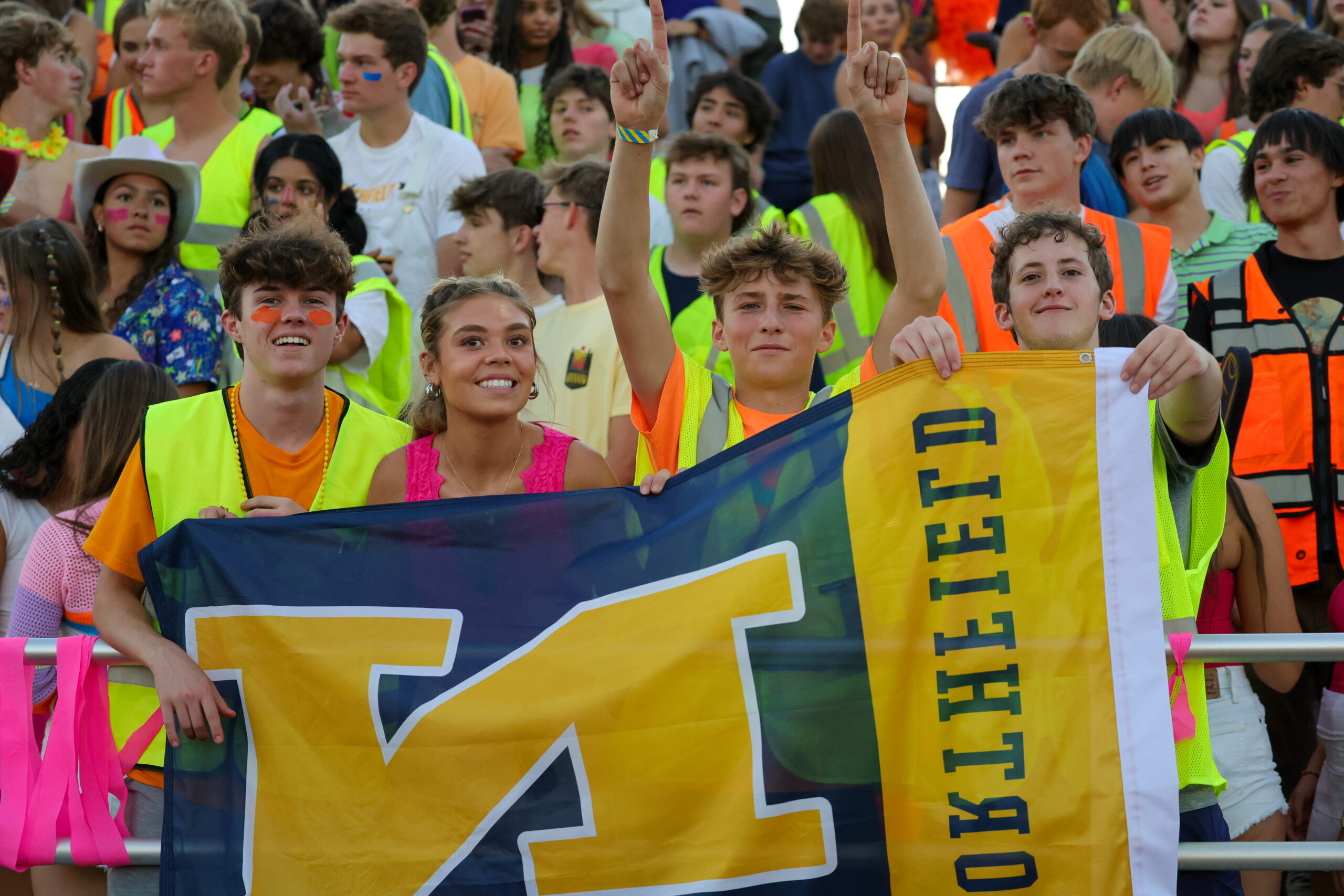 four students holding a Northfield flag at a pep rally