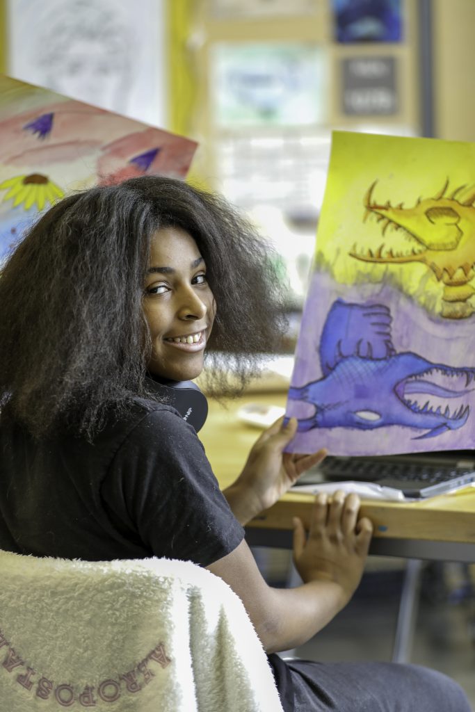 Student holding artwork turned to smile