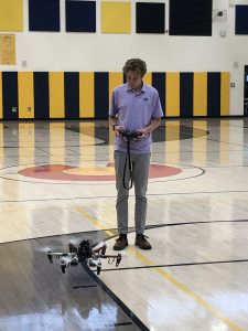Student piloting drone in gym